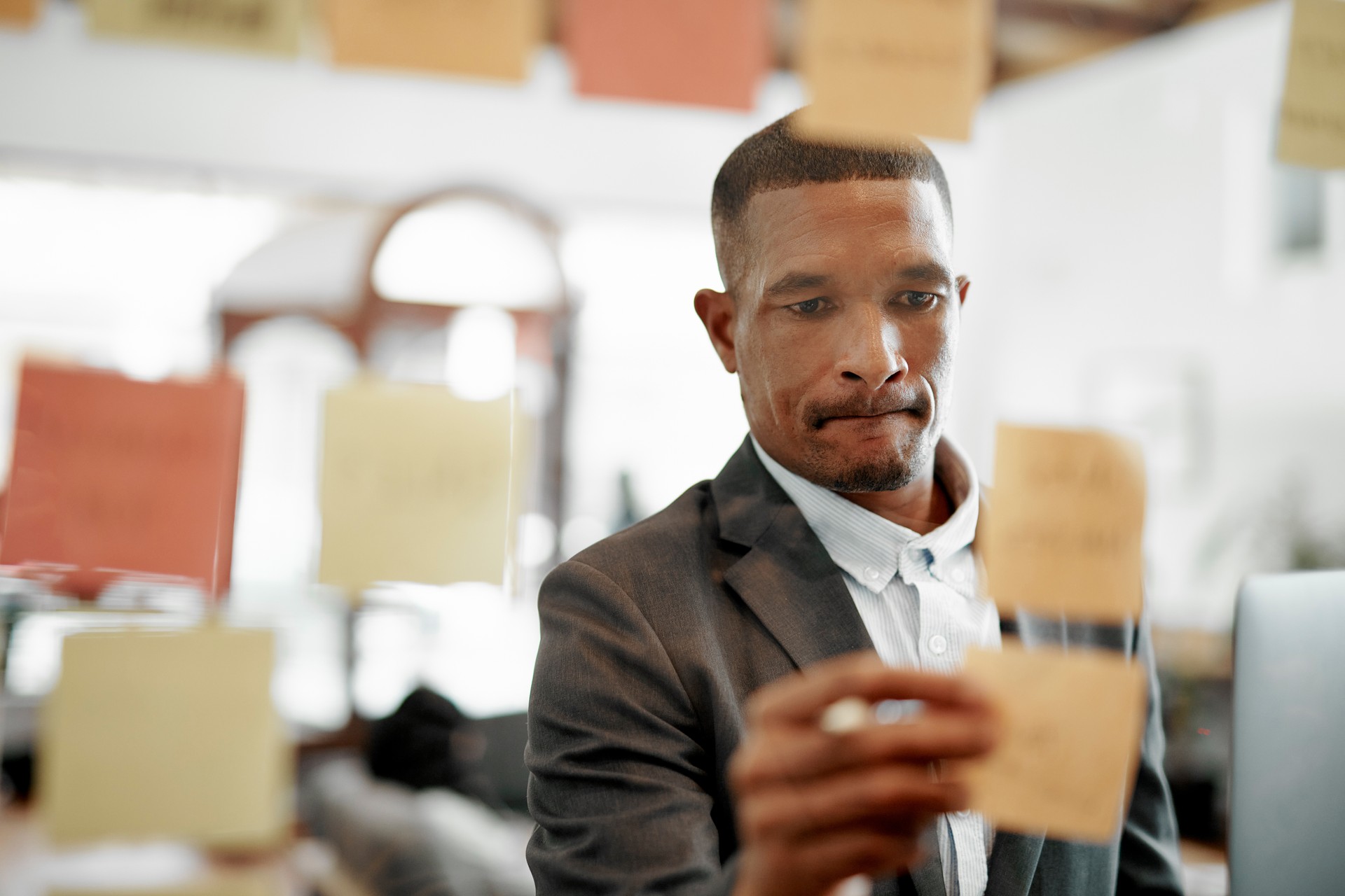 Shot of a young businessman brainstorming with notes on a glass wall in an office